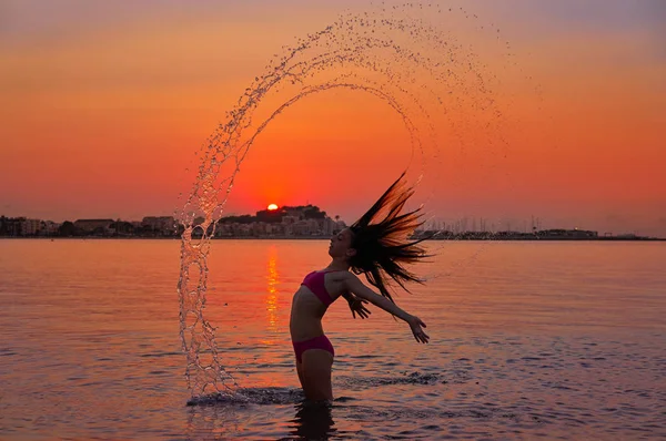 オレンジ色の空に夕日のビーチでフリップ反転髪の少女 — ストック写真