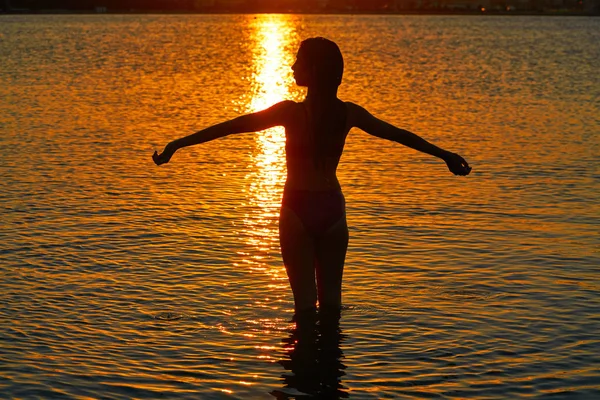ビーチ サンセット両手を広げて立っている女の子シルエット — ストック写真