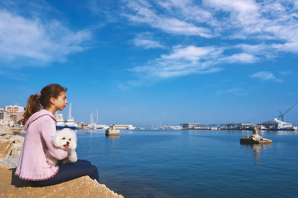 在地中海的码头岸边抱着马尔蒂钦小狗的少女 — 图库照片