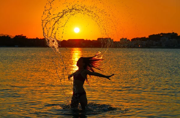 オレンジ色の空に夕日のビーチでフリップ反転髪の少女 — ストック写真