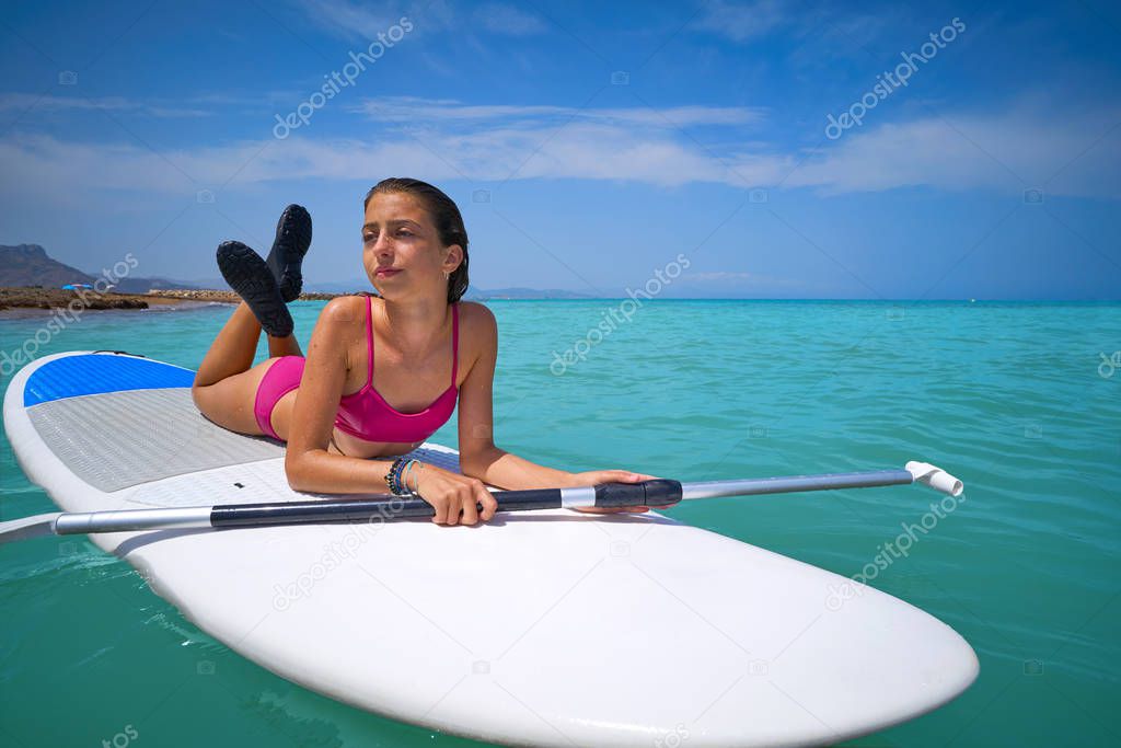 Girl relaxed lying on paddle surf board SUP relaxed in summer