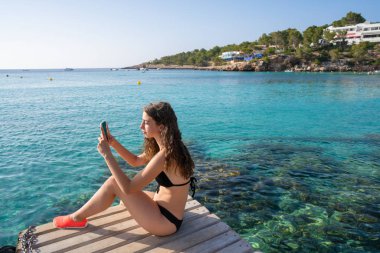Ibiza girl taking smartphone photos clipart