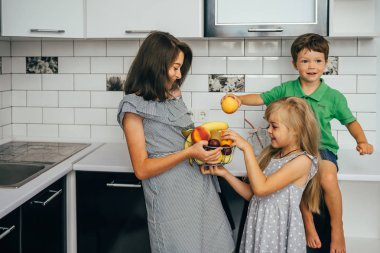 Mutlu aile taze meyve yiyor. Sağlıklı beslenme kavramı. Mutfakta meyveli çocuklar var.