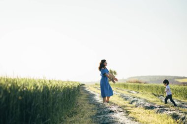 Stilish anne ve yakışıklı oğlu doğa üzerinde eğleniyor. Mutlu aile kavramı. Aile açık hava yaşam tarzı ile güzellik doğa sahne. Mutlu bir aile birlikte dinlenme. Mutluluk ve uyum içinde aile hayatı. Anneler günü.