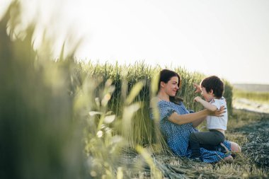 Stilish anne ve yakışıklı oğlu doğa üzerinde eğleniyor. Mutlu aile kavramı. Aile açık hava yaşam tarzı ile güzellik doğa sahne. Mutlu bir aile birlikte dinlenme. Mutluluk ve uyum içinde aile hayatı. Anneler günü.