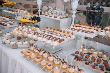 Taze, egzotik, organik meyveler, açık büfe masasında hafif atıştırmalıklar. Mini yemekler, abur cuburlar, etkinliklerde restoran yemekleri. Parti malzemeleri için dekore edilmiş nefis bir masa. Kekler ve brovniler açık büfe masasının üzerinde duruyor.