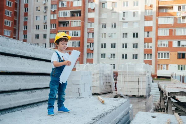 Architect in helmet writing something near new building. little cute boy on the building as an architect.