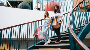 Güzel genç anne ve genç kızı alışveriş poşetleri tutuyor, alışveriş merkezinde alışveriş. Aile alışverişi.