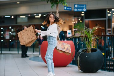 Alışveriş zamanı, alışveriş merkezinde alışveriş poşetleri olan genç kız. Alışveriş konsepti