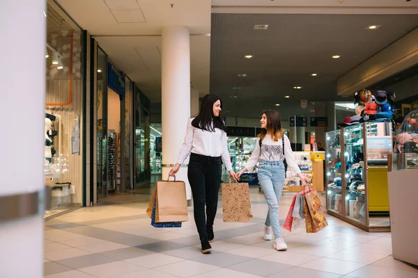 Hermosa mamá joven y la hija adolescente están sosteniendo bolsas de compras y sonriendo mientras hacen compras en el centro comercial. Compras familiares . —  Fotos de Stock