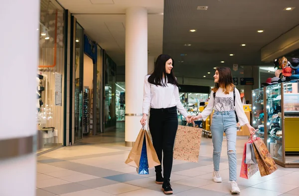 Beautiful young mom and teenage daughter are holding shopping bags, shopping in mall. Family shopping.