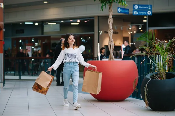 Conceito de varejo, gesto e venda - menina adolescente sorridente com muitos sacos de compras no shopping — Fotografia de Stock