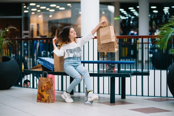Lakossági, gesztus és értékesítési koncepció-mosolygó tizenéves lány, sok bevásárló táska a plázában — Stock Fotó