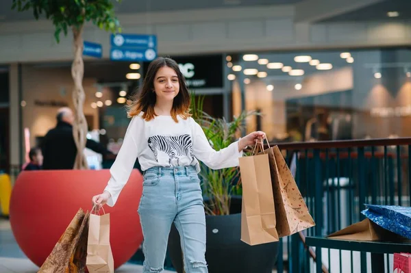 Tempo de compras, menina adolescente com sacos de compras no shopping center. Conceito de compras — Fotografia de Stock