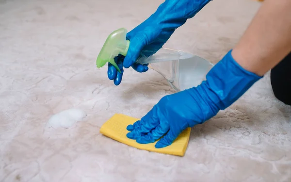 Människor, hushållsarbete och städning koncept-närbild av kvinna i gummihandskar med tyg och derergent Spray rengöring mattan hemma. närbild av kvinna med trasa rengöring mattan — Stockfoto