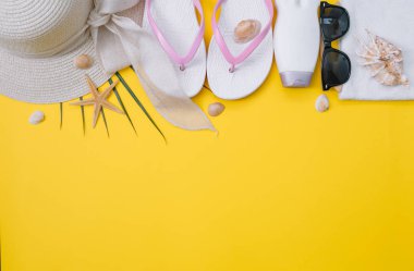 Plaj düz döşeme aksesuarları. Güneş şapkası, bej havlu, sarı kozmetik çantası, kamera, krem, güneş koruyucu şişe, tarak ve deniz kabukları. Yaz seyahati tatil konsepti