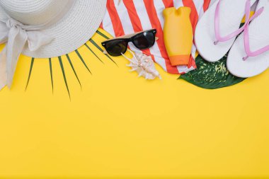 Plaj düz döşeme aksesuarları. Güneş şapkası, bej havlu, sarı kozmetik çantası, kamera, krem, güneş koruyucu şişe, tarak ve deniz kabukları. Yaz seyahati tatil konsepti