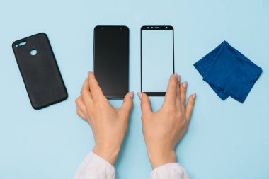 Ekranlı akıllı telefon elinde cam kapağı korur. mavi arka plan. kadın el sopa temperli cam kalkan veya cep telefonu ile film ekran kapağı. koruyucu kavramlar fikirler