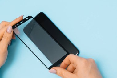 Ekranlı akıllı telefon elinde cam kapağı korur. mavi arka plan. kadın el sopa temperli cam kalkan veya cep telefonu ile film ekran kapağı. koruyucu kavramlar fikirler
