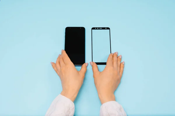 Smartphone con pantalla protege la cubierta de vidrio en las manos. fondo azul. mujer mano palo protector de vidrio templado o pantalla de película cubierta con teléfono móvil. conceptos protectores ideas — Foto de Stock