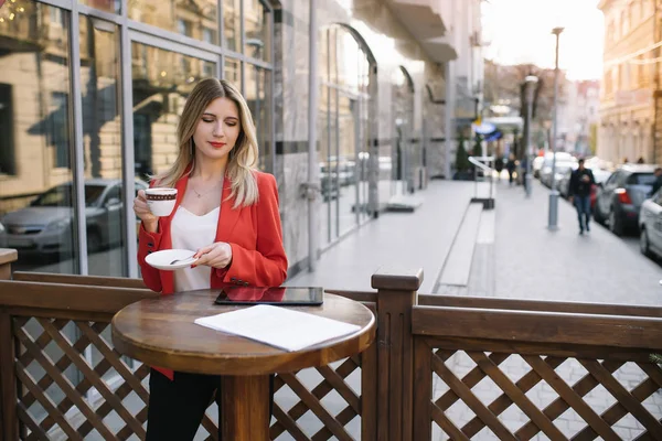 아름 다운 젊은 사업가 일회용 커피 컵, 커피, 술 및 도시의 도시 배경에 대 한 그녀의 손에 태블릿을 들고. — 스톡 사진