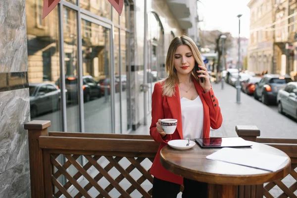 Empresaria tomando un descanso para tomar un café y usando un teléfono inteligente . — Foto de Stock