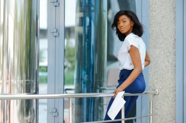Güzel siyahi kadın şehir arka planında tablet bilgisayar kullanıyor. Başarılı kadın konsepti.