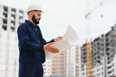 İşçi ve bulanık inşaat arkaplanı mavi gökyüzünde