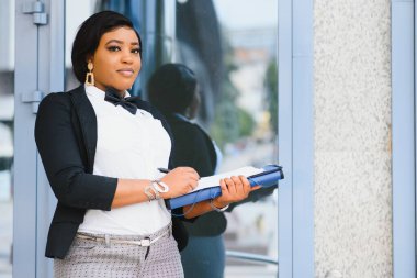 Ofis binasının yakınında başarılı bir profesyonel pozu. Genç Afrikalı Amerikalı iş kadını dışarıda duruyor. Kadın iş adamı konsepti