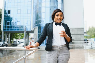 Ofis binasının yakınında başarılı bir profesyonel pozu. Genç Afrikalı Amerikalı iş kadını dışarıda duruyor. Kadın iş adamı konsepti