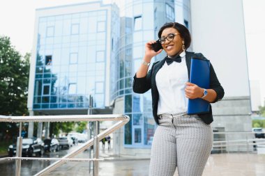 Ofis binasının yakınında başarılı bir profesyonel pozu. Genç Afrikalı Amerikalı iş kadını dışarıda duruyor. Kadın iş adamı konsepti