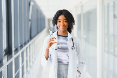 Hastane koridorunda steteskobu olan kadın doktor elinde arka planda ameliyat odası olan bir pano, sağlık ve tıbbi konsept, seçici odaklanma..