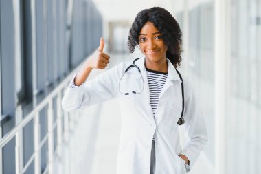 Kendine güvenen Afro-Amerikan kadın doktor profesyonel hasta notları hastane koridorlarının arka planında izole edilmiş. Pozitif yüz ifadesi