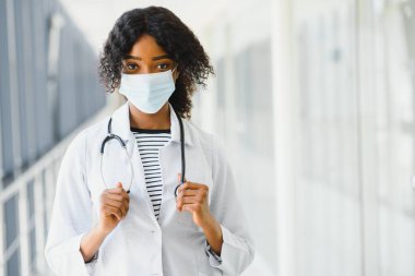 Hastane koridorunda steteskobu olan kadın doktor elinde arka planda ameliyat odası olan bir pano, sağlık ve tıbbi konsept, seçici odaklanma..