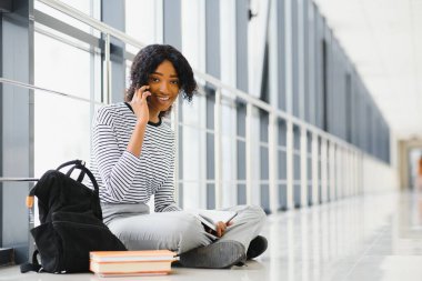 Afro-Amerikan öğrencinin yan görünüşü koridorda oturup kitap okuması.