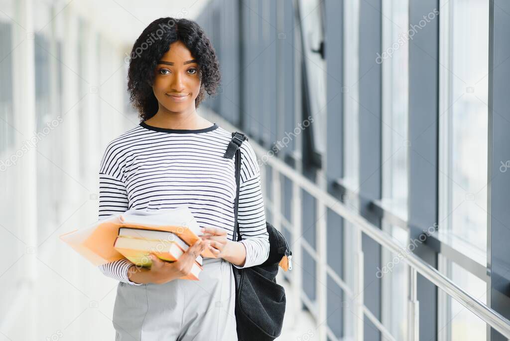 Portrait of african female college student with curly black hair in bright corridor