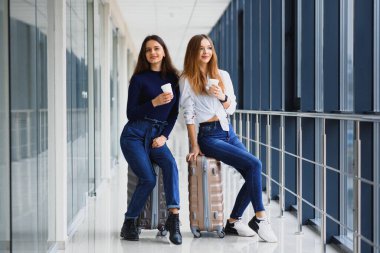 Havaalanındaki iki kadın uçağa biniyor. Havaalanında bavulları olan kız arkadaşlar.