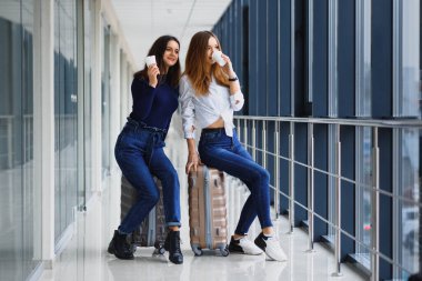 Havaalanındaki iki kadın uçağa biniyor. Havaalanında bavulları olan kız arkadaşlar.