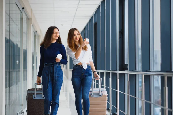 Two women at the airport go on a plane. girlfriends at the airport with suitcases