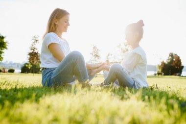 Mutlu anne ve kız parkta dinleniyor. Bahar ya da yaz mevsiminde aile hayatı olan güzel doğa manzarası. Mutlu bir aile birlikte dinleniyor, dışarıda eğleniyor..