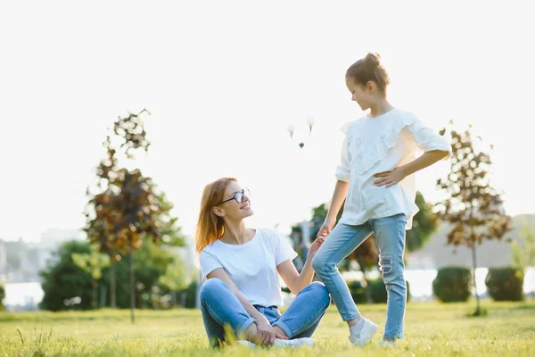 自然界で幸せと優しい家族 感情的で若い母親は彼女の笑顔の小さな娘が芝生の上に横たわって抱擁します サマーパーク 肯定的な感情 小児期 ライフスタイル — ストック写真