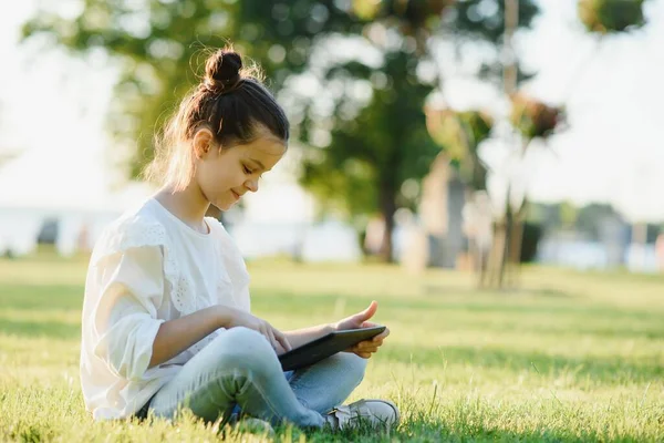 Klein Meisje Zit Gras Spelen Tablet Toning Foto — Stockfoto