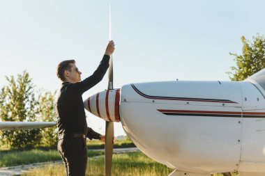 Düşünceli genç pilot küçük bir uçağın yanında duruyor.