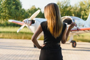 Zarif elbiseli zengin bir kadın limuzin ve özel hayatın karşısında duruyor.