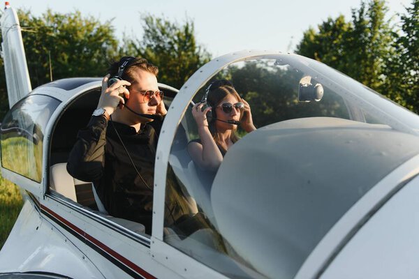 Young woman and pilot in in the cockpit of a plane. Front view