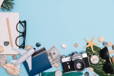 Seyahat konsepti, saat, uçak, para, pasaport, kalem, kitap, fotoğraf çerçevesi, mavi arkaplanda fotokopi alanı olan gözlük hazırlığı.