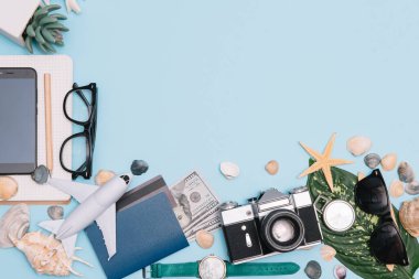Seyahat konsepti, saat, uçak, para, pasaport, kalem, kitap, fotoğraf çerçevesi, mavi arkaplanda fotokopi alanı olan gözlük hazırlığı.