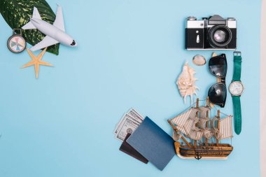 Seyahat konsepti, saat, uçak, para, pasaport, kalem, kitap, fotoğraf çerçevesi, mavi arkaplanda fotokopi alanı olan gözlük hazırlığı.