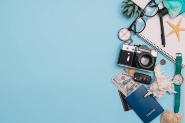 Seyahat konsepti, saat, uçak, para, pasaport, kalem, kitap, fotoğraf çerçevesi, mavi arkaplanda fotokopi alanı olan gözlük hazırlığı.