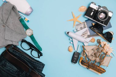 Seyahat konsepti, saat, uçak, para, pasaport, kalem, kitap, fotoğraf çerçevesi, mavi arkaplanda fotokopi alanı olan gözlük hazırlığı.